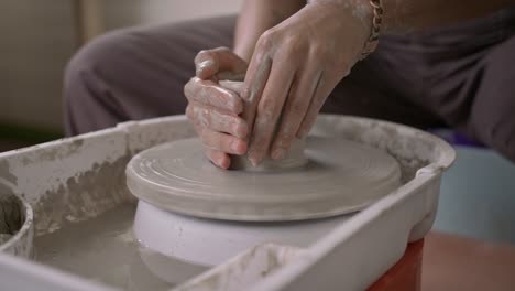 potter adds water to wet clay on rotating wheel to create earthenware pot slow motion