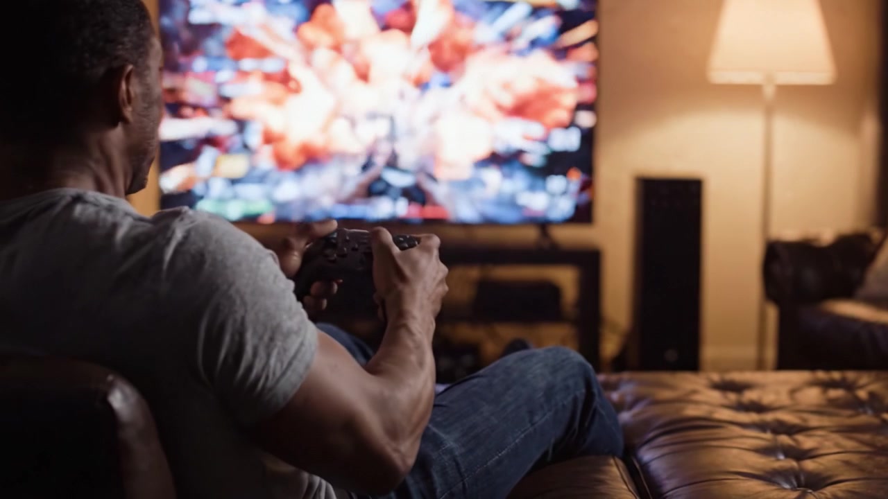 Immerso nel gioco: un giocatore completamente immerso in un'intensa sessione di videogioco mentre immagini drammatiche esplodono sullo schermo, catturando l'emozione dell'intrattenimento interattivo