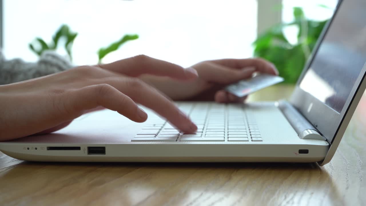 Close-up of a girl's hands holding a credit card and using a laptop while