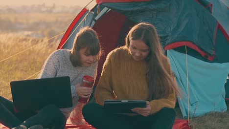 Chicas-Excursionistas-Con-Computadora-Portátil-Y-Tableta-En-La-Carpa-Azul-A-Cámara-Lenta