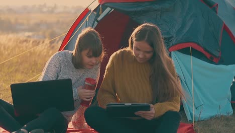 girls hikers with laptop and tablet at blue tent slow motion