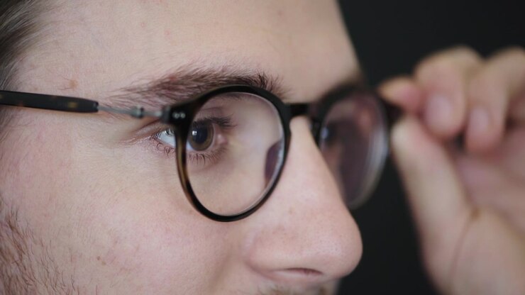 Young Man Putting On Tortoiseshell Glasses