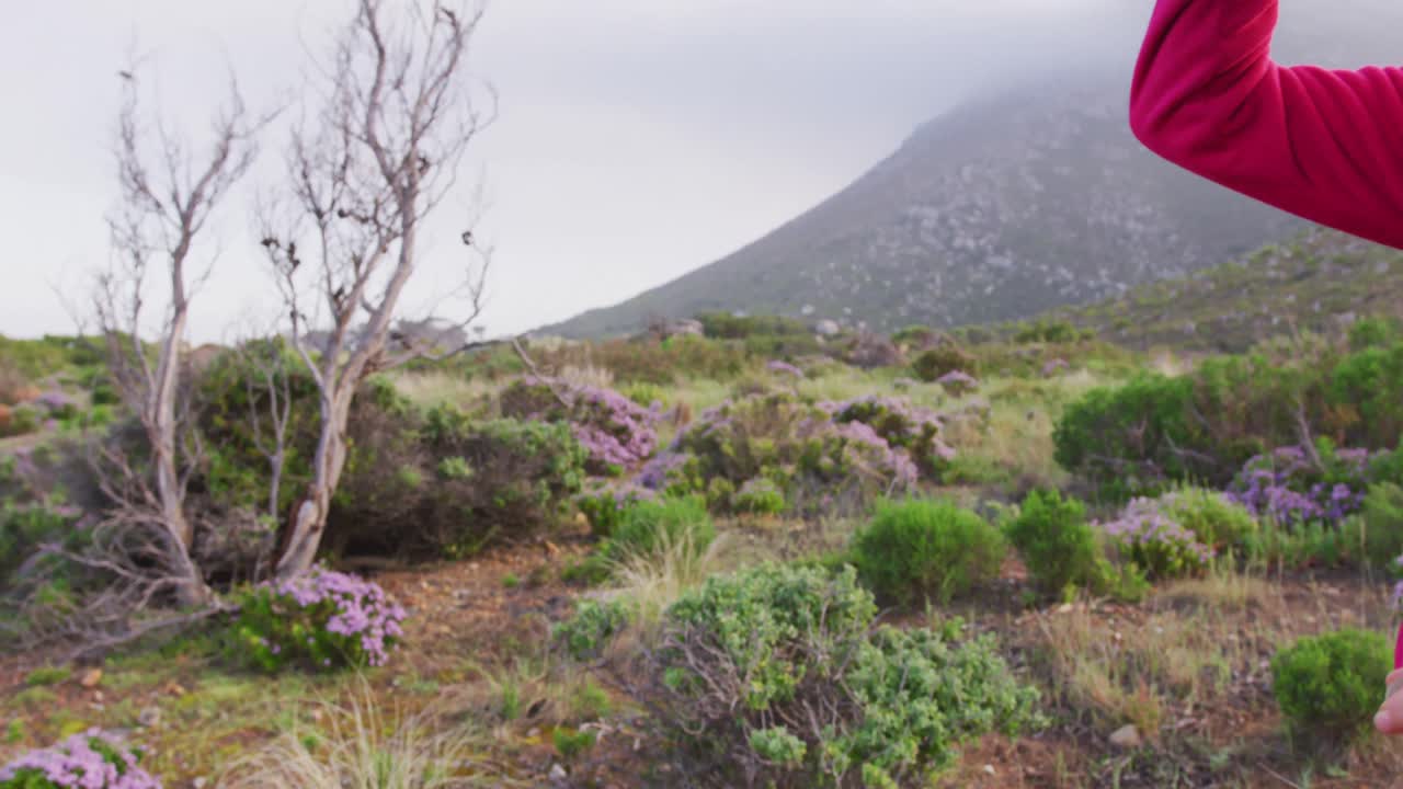 una mujer excursionista mayor mirando a la distancia mientras hace senderismo en las montañas.