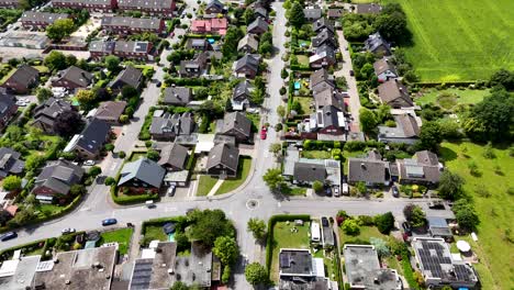 single family houses with solar panels on roof in quiet suburb district of town. rural fields border. aerial top down flyover. row of homes and townhouses in subdivision residential area