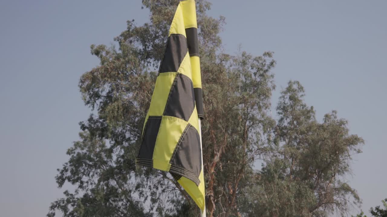 una bandera de golf a cuadros negra y amarilla con un movimiento sutil