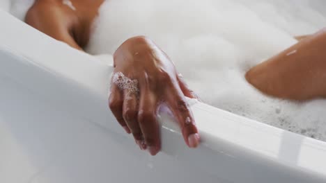 primer plano de una mujer afroamericana relajándose en la bañera en el baño en casa