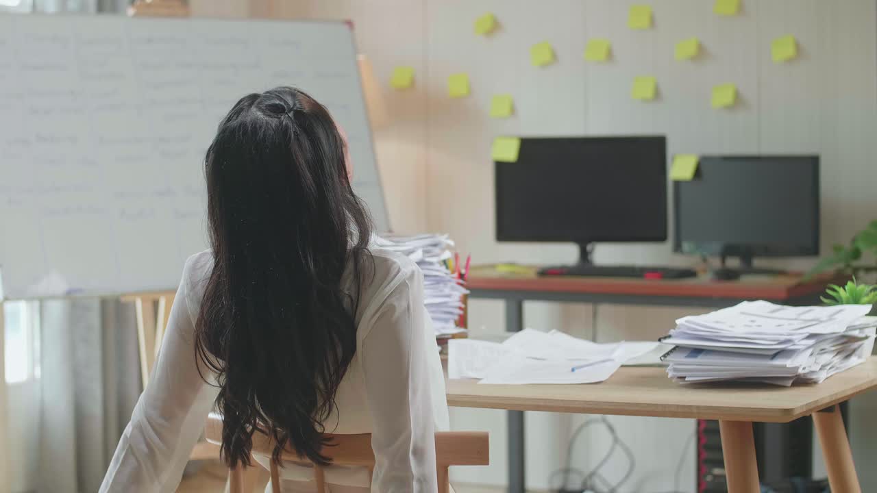 문서 를 열심히 작업 하는 동안 의자 에 기대어 잠을 자고 있는 아시아인 여자 의 뒷면
