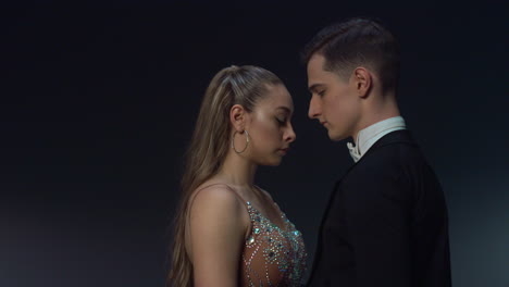 attractive dancers looking eye to eye. ballroom dancers standing on dark stage.