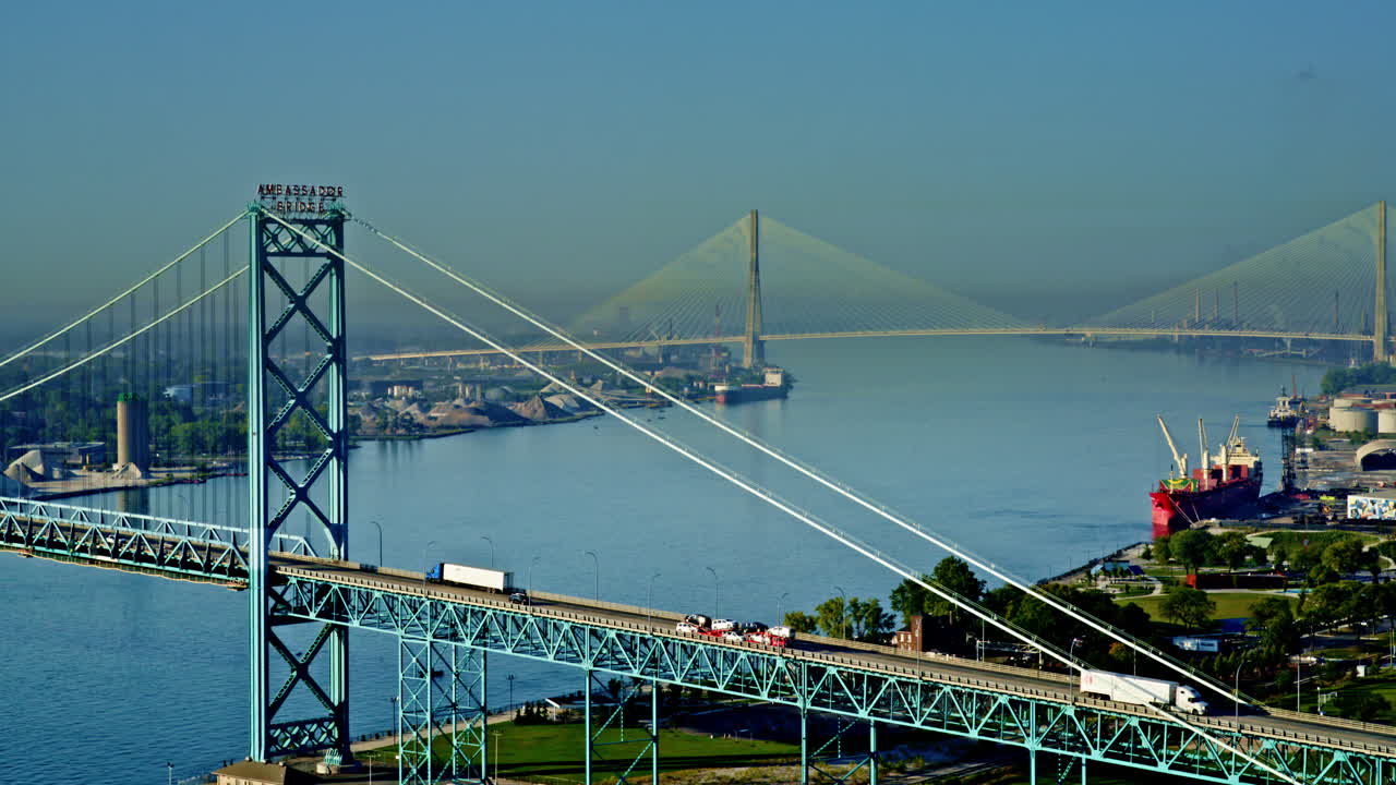 Drone shot descending over Detroit River, revealing freighter and city skyline below