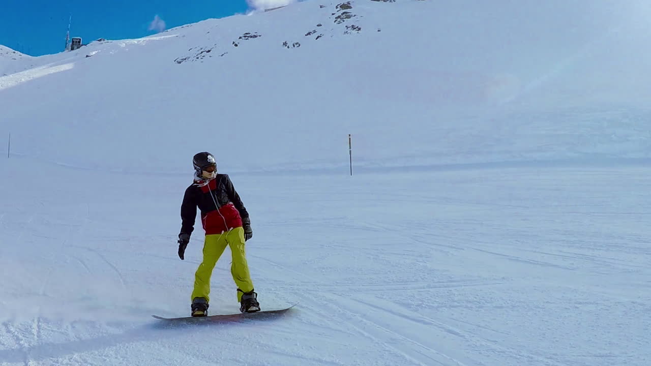 snowboarder deslizándose cuesta abajo en un día soleado en cámara lenta