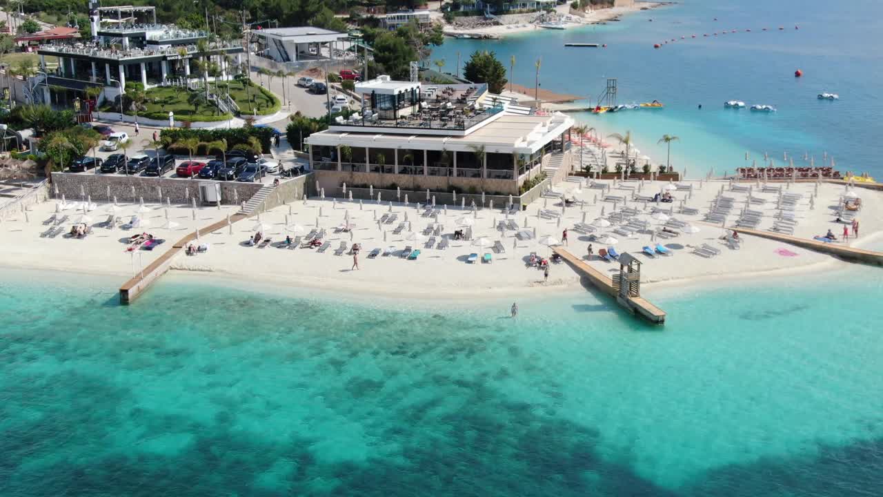 알바니아에서 드론이 하 모래 해변, 푸른 크리스탈 은 물, 보트 및 호텔을 날아다니는 풍경.