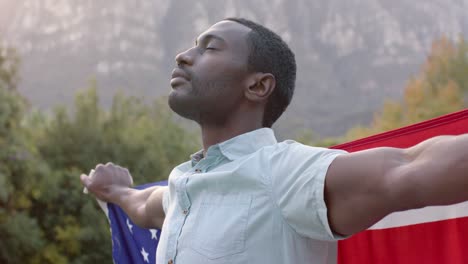 portrait of african american man holding flag of usa in garden, slow motion