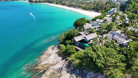 drone captures stunning aerial views of phuket's coastline, showcasing turquoise waters, lush greenery, and luxurious villas under bright sunlight