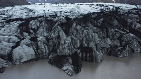 edge of retreating glacier in iceland covered with black sand, global warming