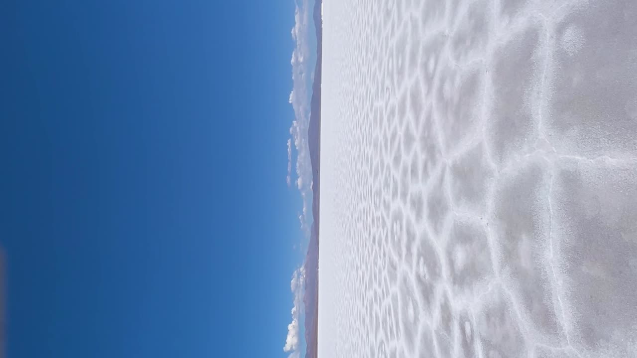 expansivas llanuras blancas de sal y drones voladores bajo un cielo azul claro en salinas grandes, argentina
