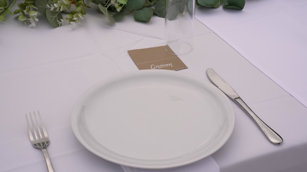 A beautifully arranged table awaits guests, featuring white tableware, elegant cutlery, and floral accents. The setting is perfect for a memorable celebration or gathering