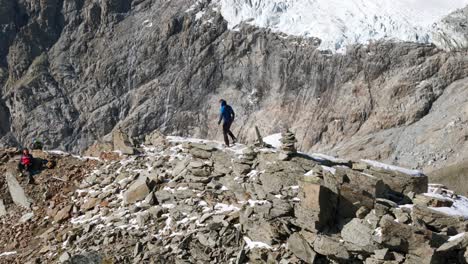 explorer walking on snowy edge of mountain top with breathtaking views of alps range in background, cima fontana, valmalenco in italy