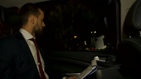 businessman at night in the back seat of his limousine