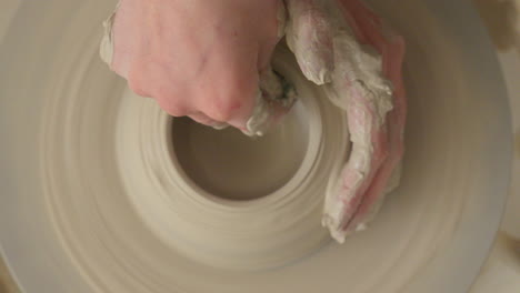 ceramics artist making a bowl on a potters wheel with both hands