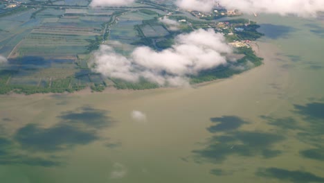 a view of the upper plane window while floating in the air, overlooking the mountains and natural water resources along the coast of thailand