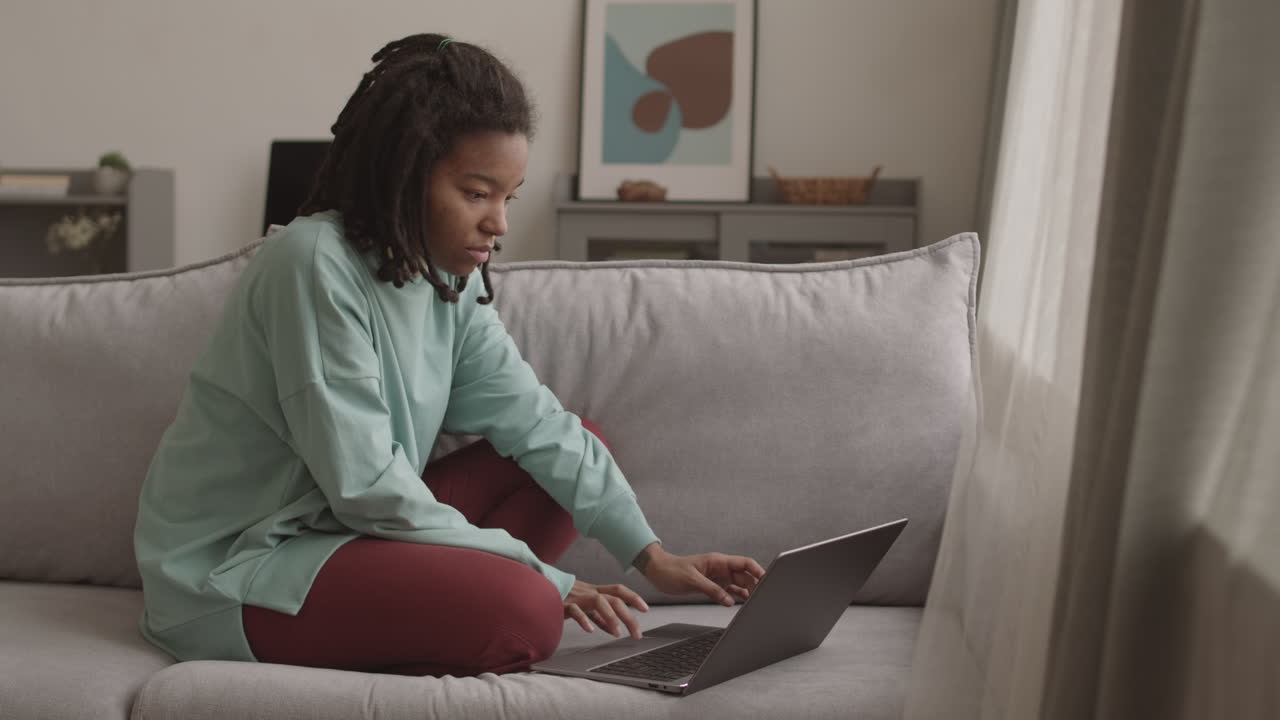 Cheerful African Woman Messaging with Friend Using Laptop