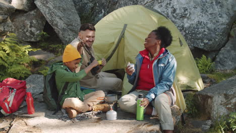 multiethnic family chatting and using binoculars at campsite