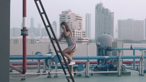 slim woman walks on hotel blue roof past colorful pipes