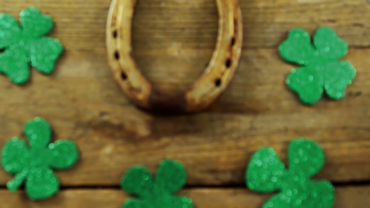 Horse shoe  surrounded by shamrocks on wooden table for st patricks