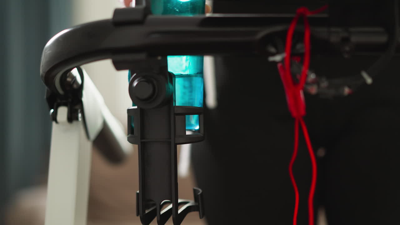 mujer se acerca a la cinta de correr con una botella de agua. deportista pone la botela de agua en el soporte de la máquina de equipo deportivo en casa. condición de vida equilibrada