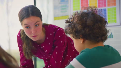 maestra hablando con un grupo de estudiantes multiculturales en la lección en el aula