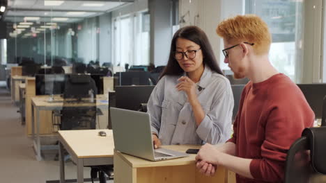 coworkers discussing project on laptop