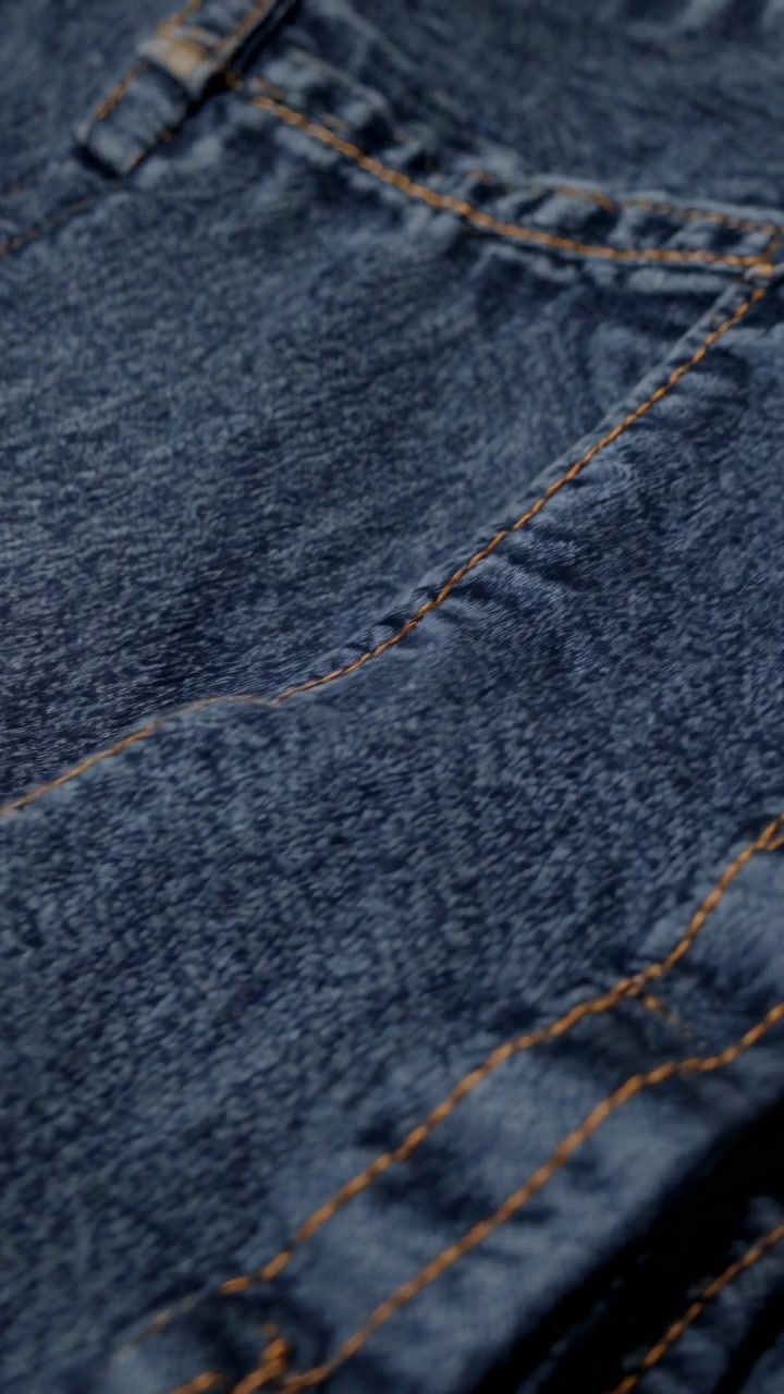 Primo piano di tessuto denim blu con cuciture arancioni
