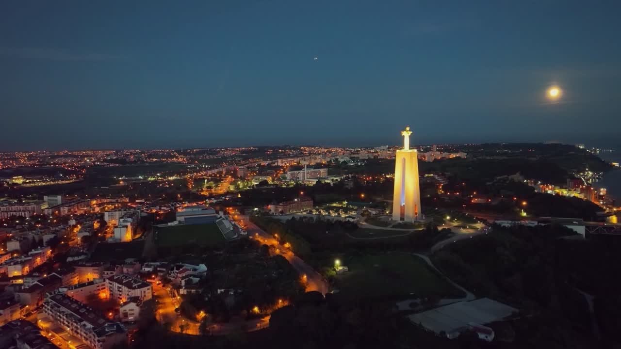 imágenes de drones, avanzando, filmando, estatua de cristo rey, la luna y las luces de la calle en almada, antes del amanecer