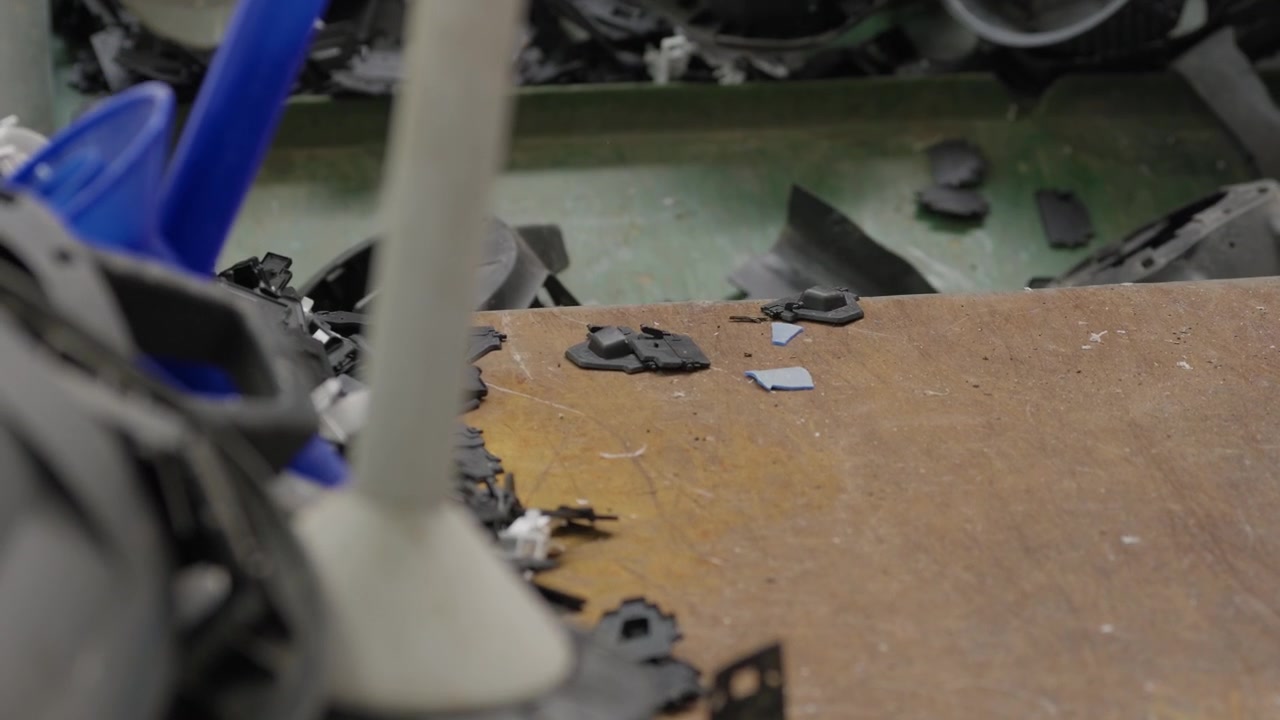 Shredded plastic pieces and blue containers scattered on worktable at plastic recycling plant