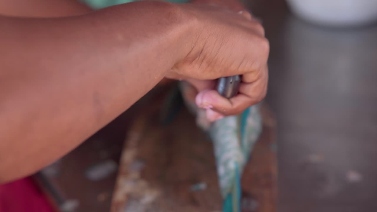 Mani che puliscono il pesce con il coltello.