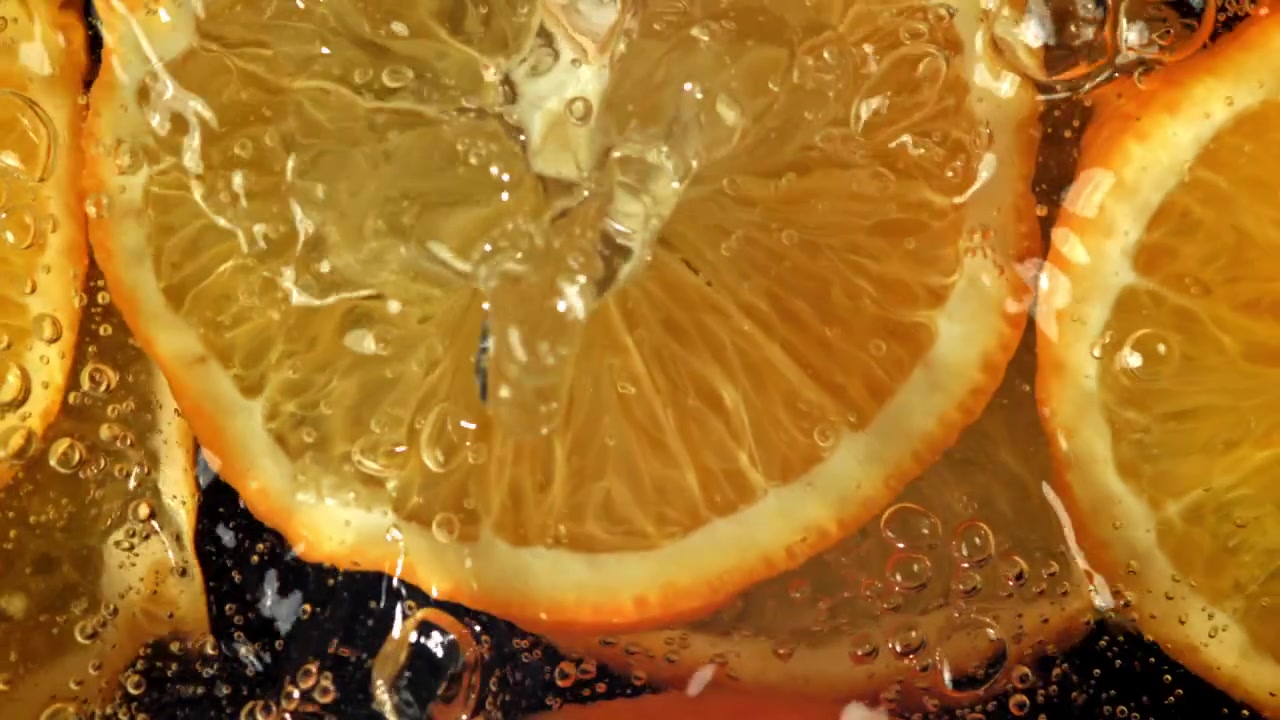 Fette d'arancia vivaci in acqua frizzante con bollicine che salgono