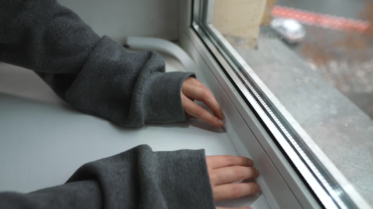 창문에 날씨 스트립을 설치하는 사람