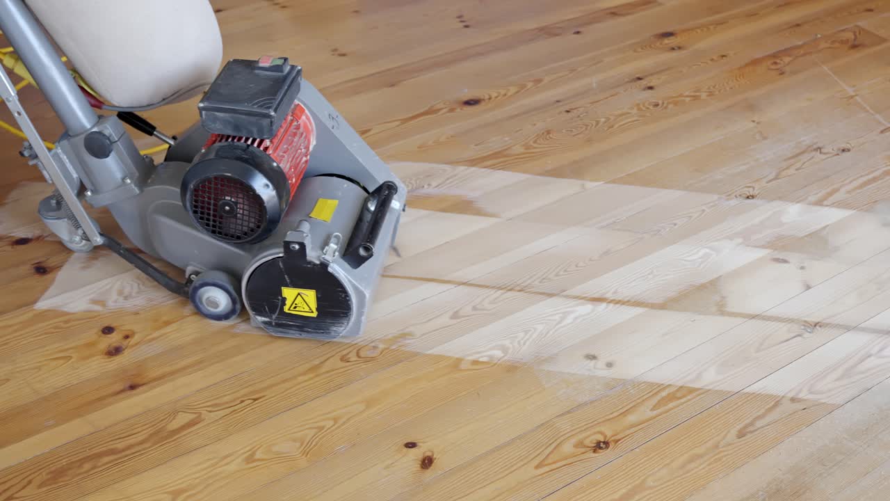 Close-up view of feet and a sanding machine in action, smoothing a wooden floor during cleaning.