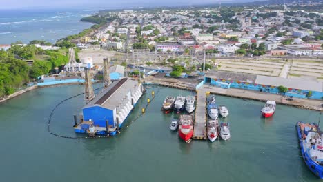 Toma-Aérea-Descendente-Del-Puerto-Industrial-De-Puerto-Plata-Con-El-Mar-Caribe-De-Fondo