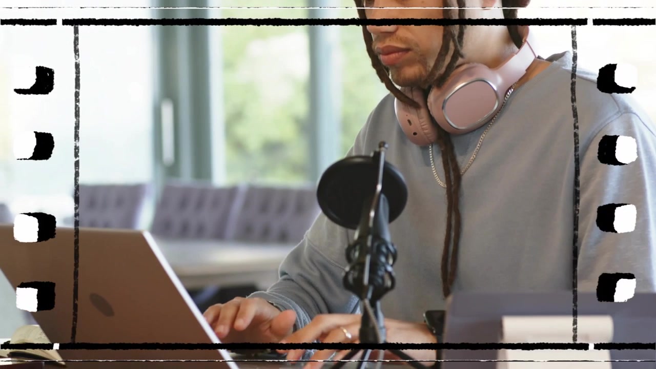 Man adjusting microphone then typing on laptop, preparing podcast episode with headphones