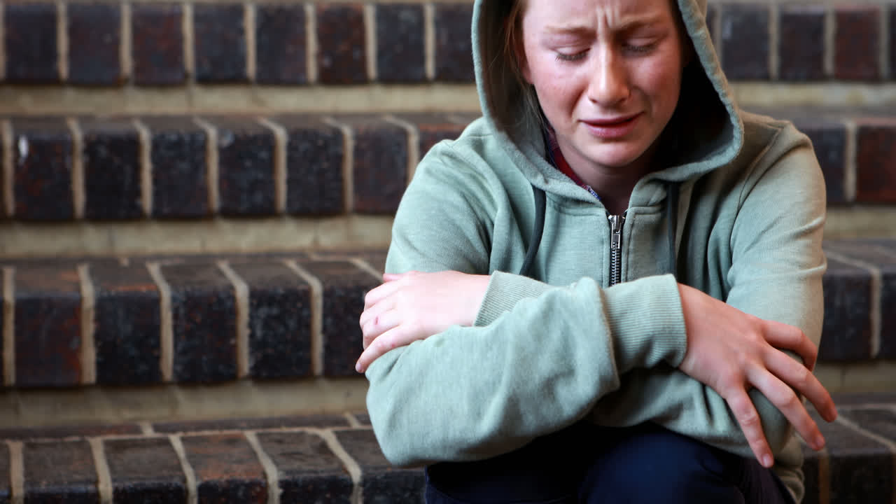 Sad schoolgirl sitting alone on staircase