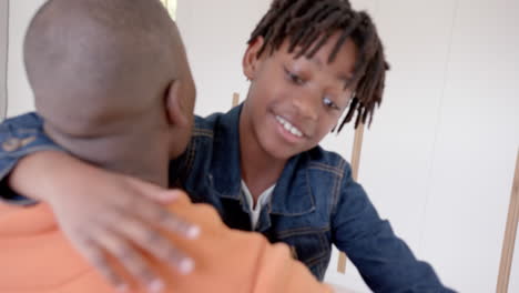 happy african american father and son embracing at home, slow motion