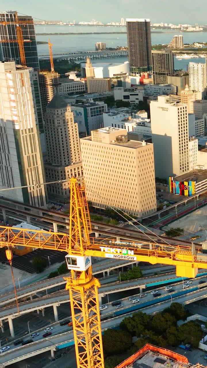 Miami, Florida, USA - January 05, 2024: Buildings and streets with transport in the city center. Construction site with tower crane. Evening view of skyscrapers. Vertical video
