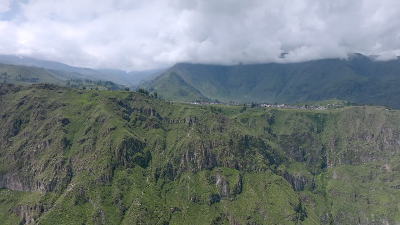 Drone shot from a greater distance, offering a sweeping view of the start of the trekking path from Cabanaconde, with the vast expanse of the Colca Canyon and the winding trail toward Sangalle.