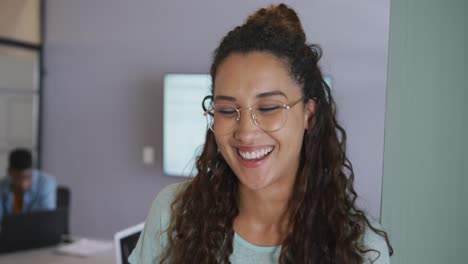 Portrait-of-smiling-biracial-creative-businesswoman-wearing-glasses,-in-meeting-room