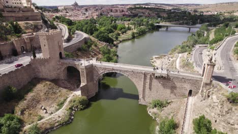 Aerial-establishing-shot-of-Puente-de-Alcantara-Roman-arch-bridge,-Toledo,-Spain