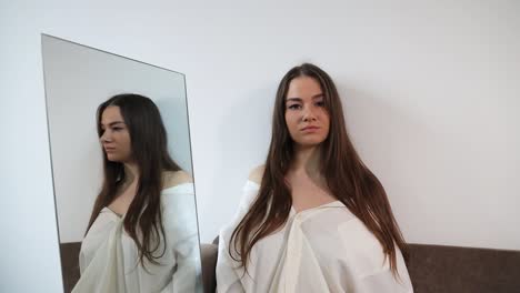 Calm-and-serious-looking-woman-sitting-next-a-mirror