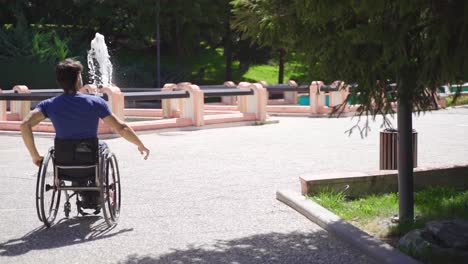 young disabled person walking in wheelchair in city park in slow motion.