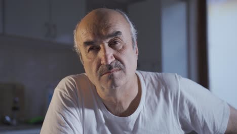 rostro cercano de un anciano solo en casa perdido en pensamientos tristes.