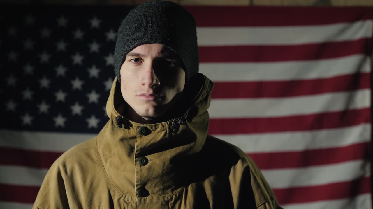 la silueta de un hombre -- mira la bandera americana en la pared de ladrillos la vista desde atrás